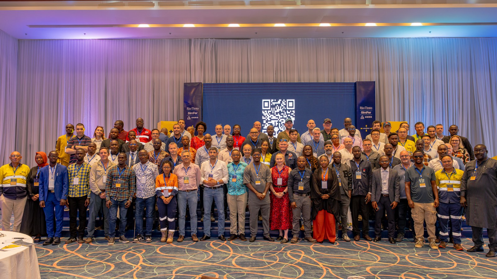 Group photo of participants at the Rio Tinto SimFer Safety Forum, gathered in front of a Simandou project branded backdrop in Conakry.