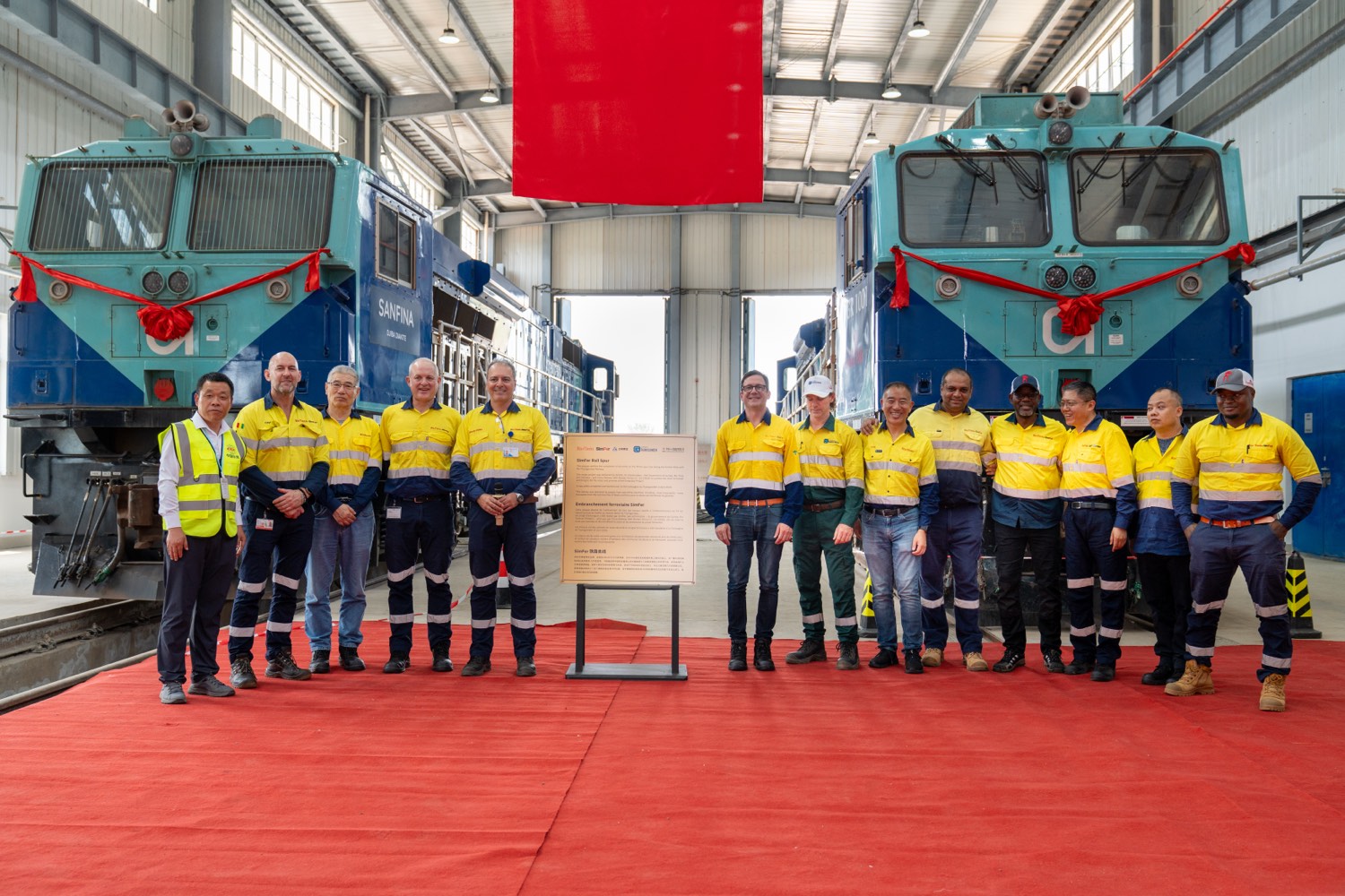 The SimFer team at the ceremony celebrating the completion of the rail spur, in front of two SimFer locomotives.